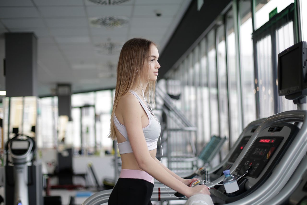 A young woman exercises on a treadmill in a modern gym, promoting fitness and a healthy lifestyle.